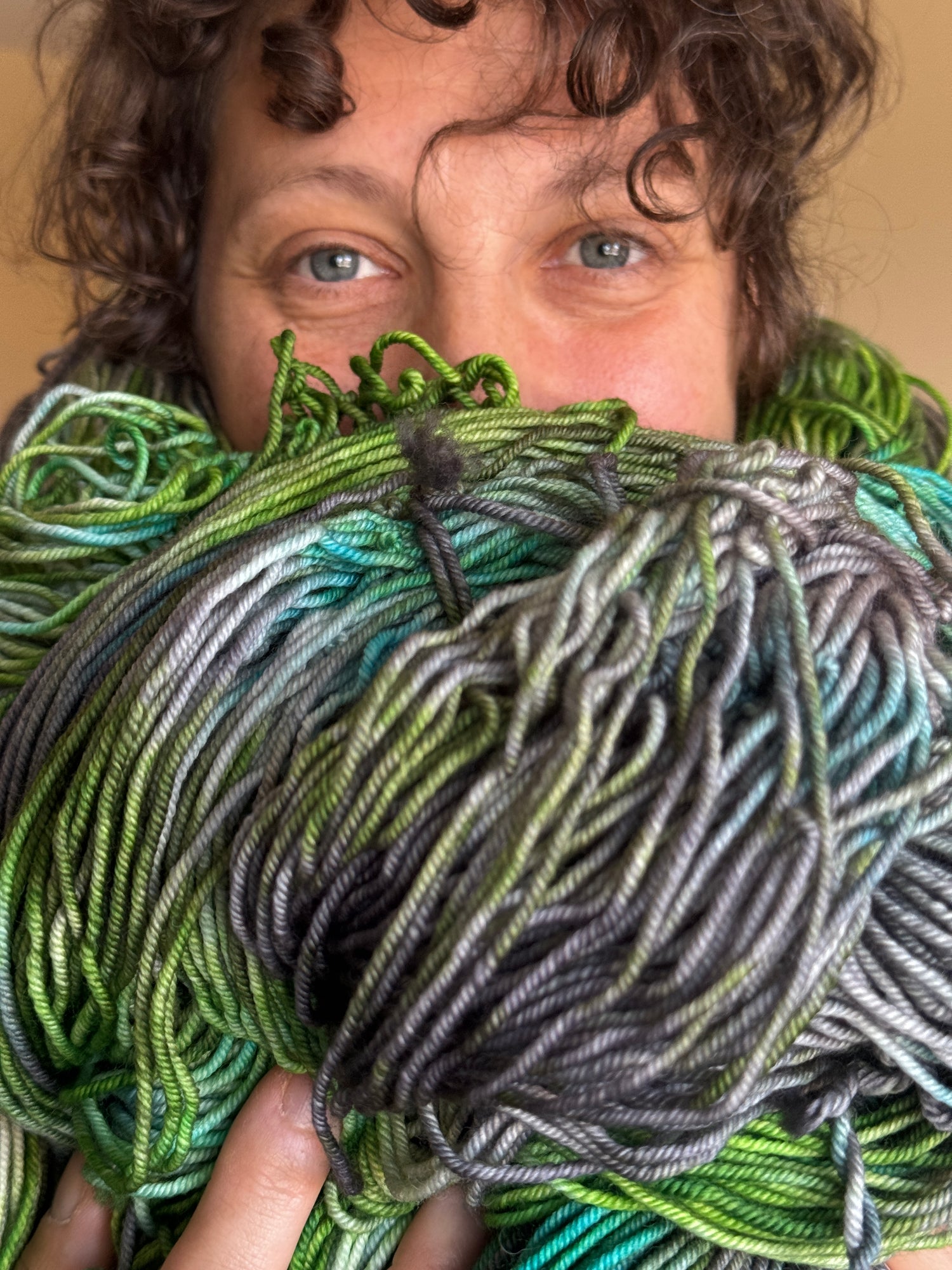 Person holding a large ball of green and gray yarn